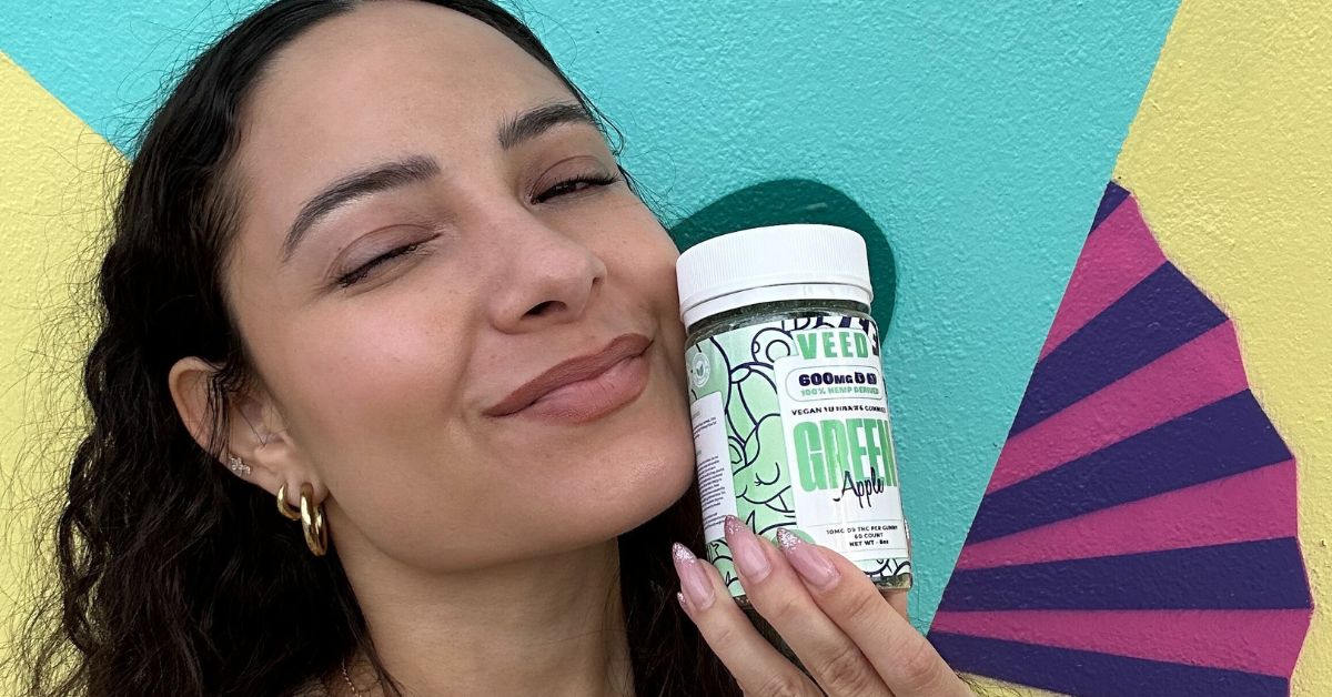 Smiling woman holding VEED THC gummies jar for mental wellness