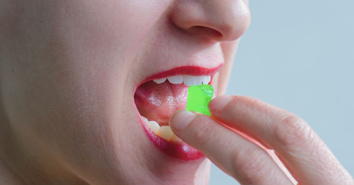 Person eating neon green THC gummy for the blog, "HOW MUCH IS TOO MUCH THC IN ONE SERVING?