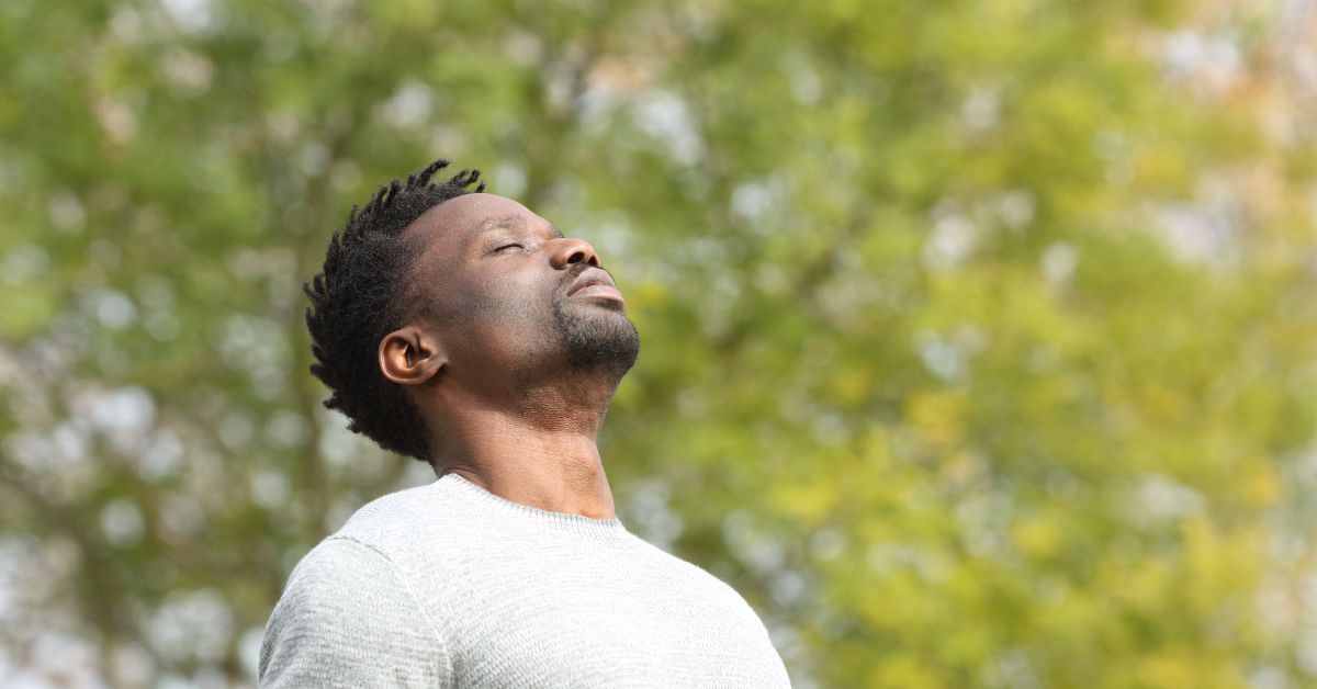 Man outdoors taking a deep breath of fresh air, symbolizing lung health and the benefits of THC edibles compared to smoking.