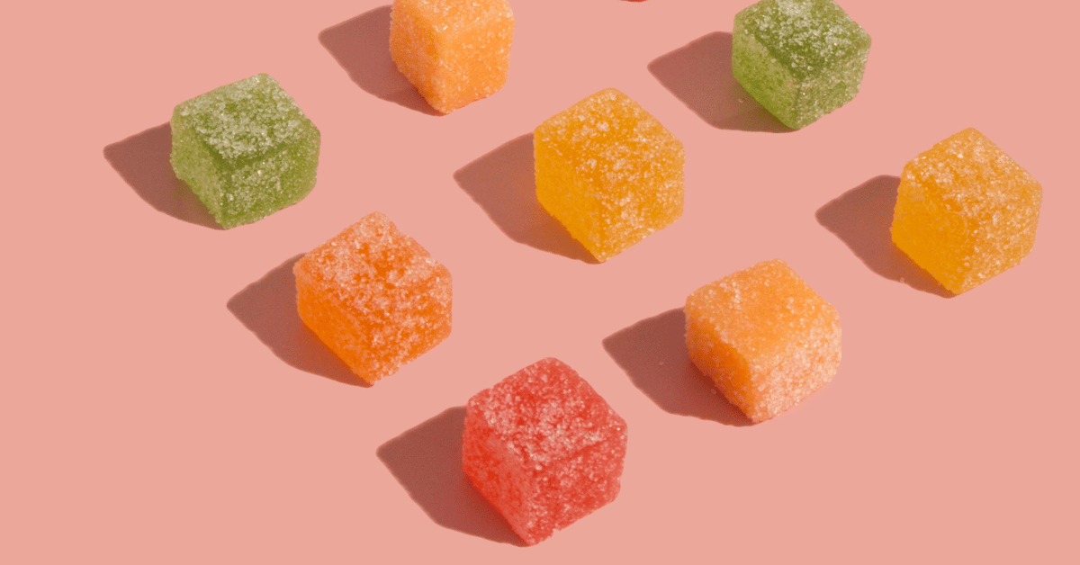 Colorful THC gummy edibles in cube shapes on a pink background