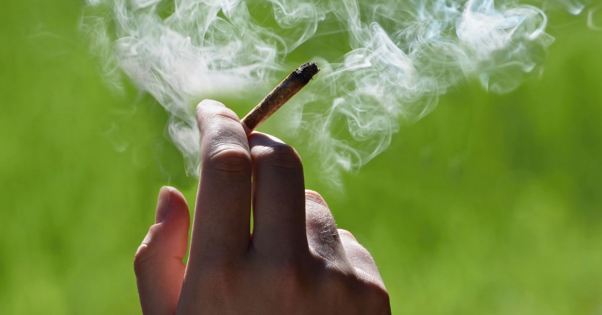 An image of a joint in someones hand representing quitting smoking with THC gummies